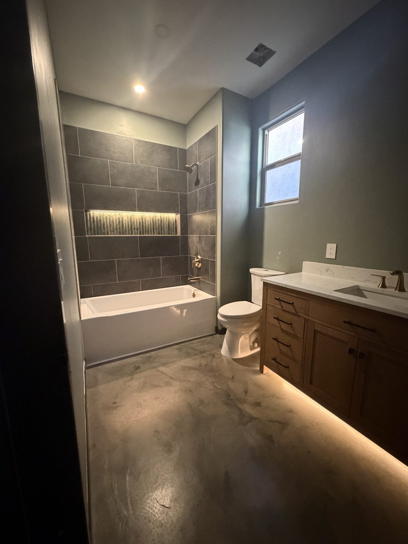 Finished bathroom with tile, stained concrete floor, and full-length LED lighting